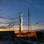 Solid rocket installed on metal launch construction in spaceport and ready for taking off against colorful sunset sky